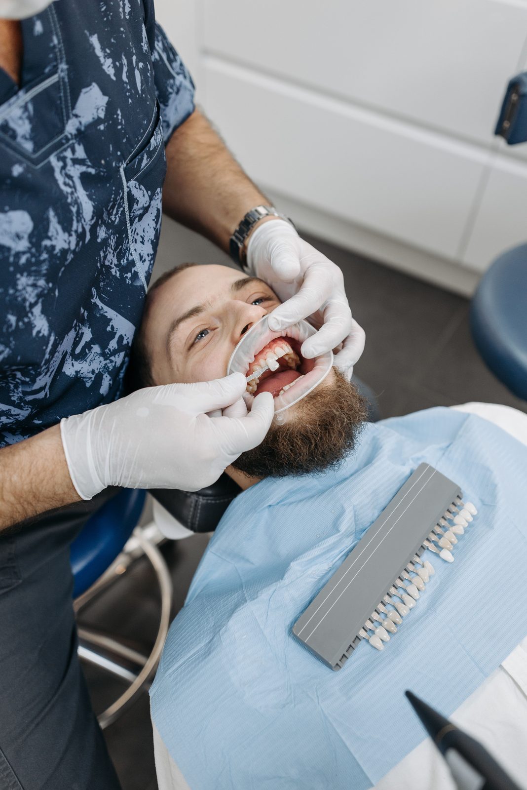 Paciente na cadeira com afastador labial durante avaliação da cor dos dentes